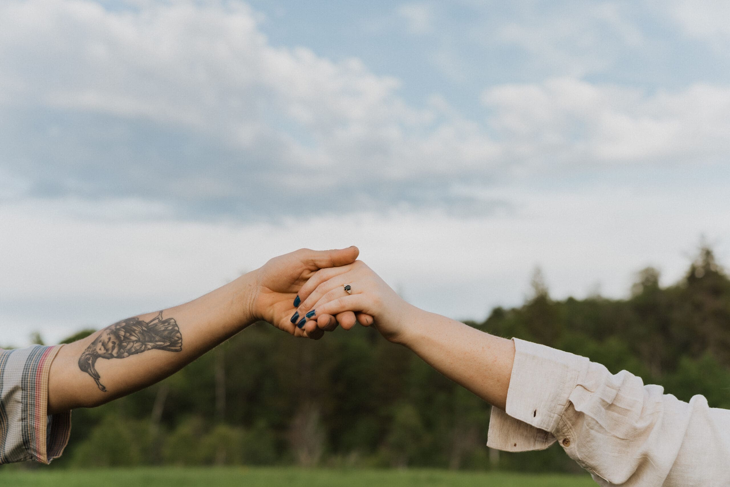 Detail shot of the couple’s intertwined hands with wildflowers blurred in the background