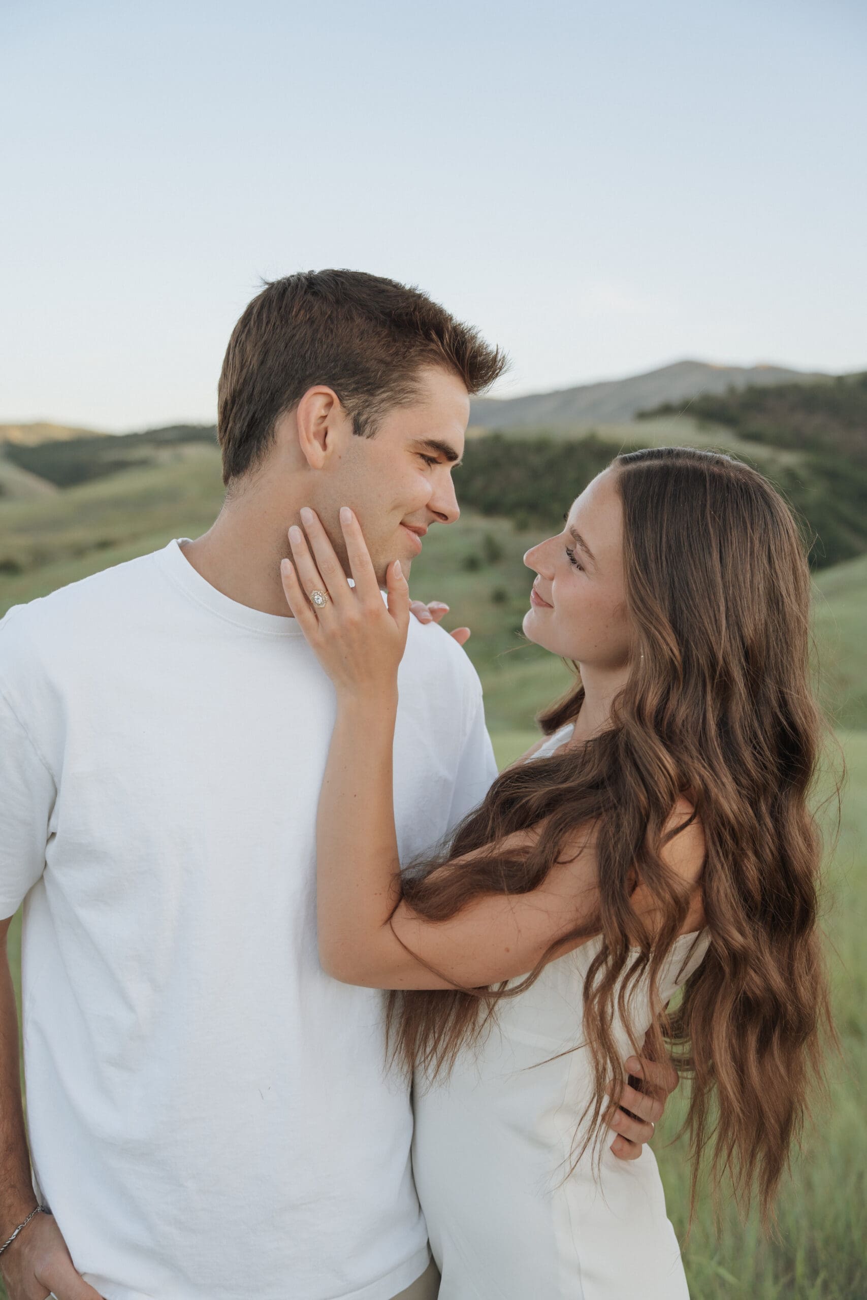 Close-up of couple's hands showing engagement ring in a grassy field