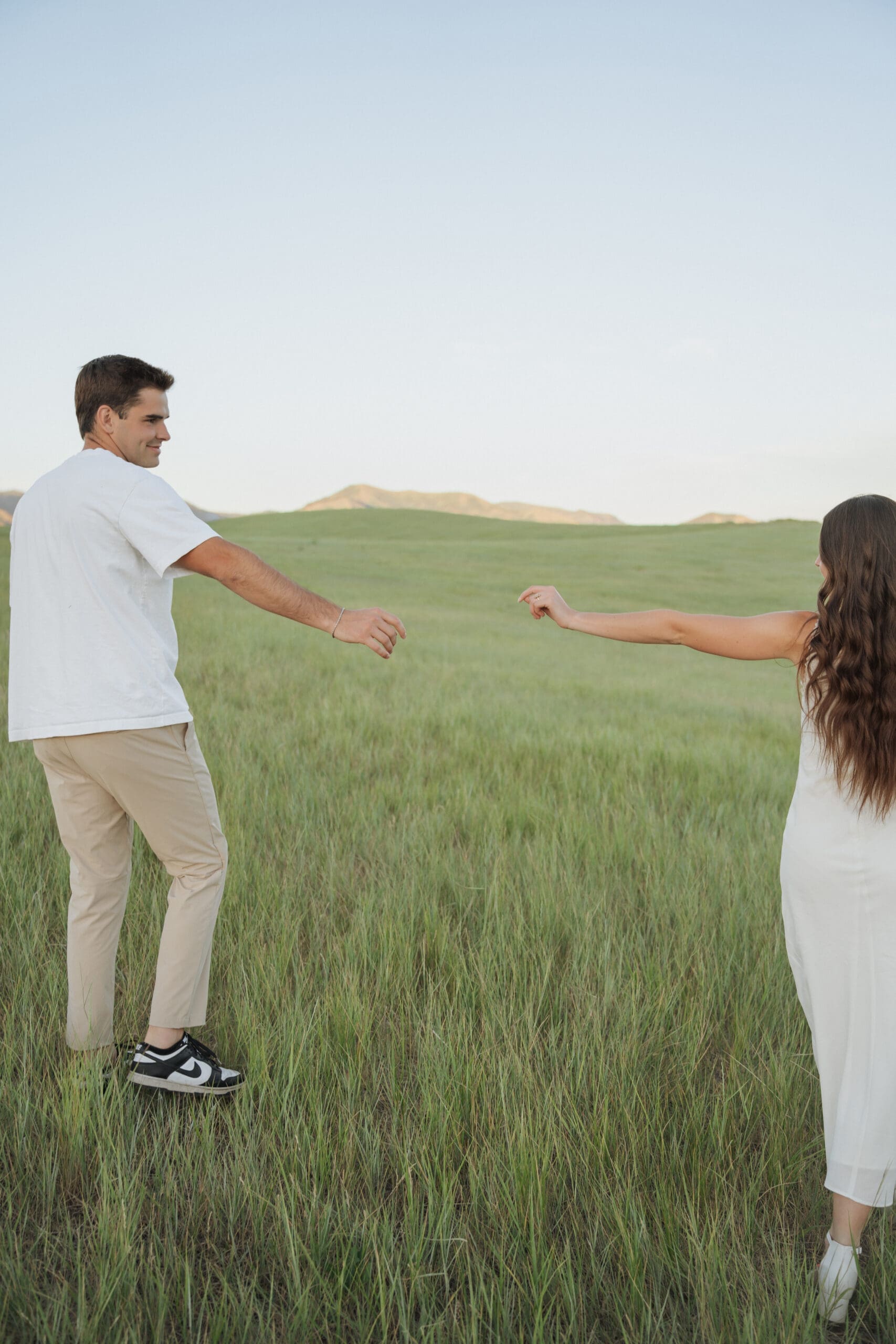 couple reaching out their arms to hold eachother in a golden meadow