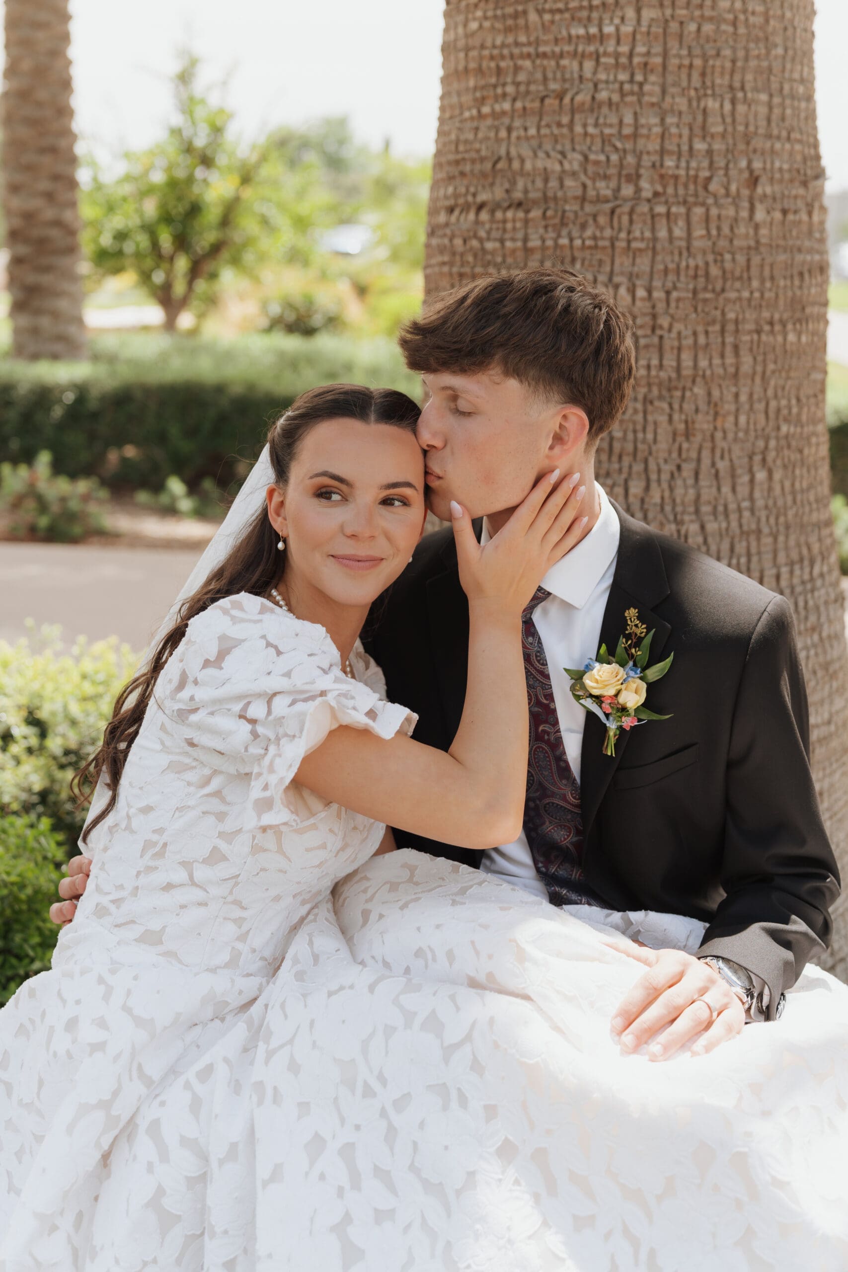 husband kissing wife on the head after their temple wedding